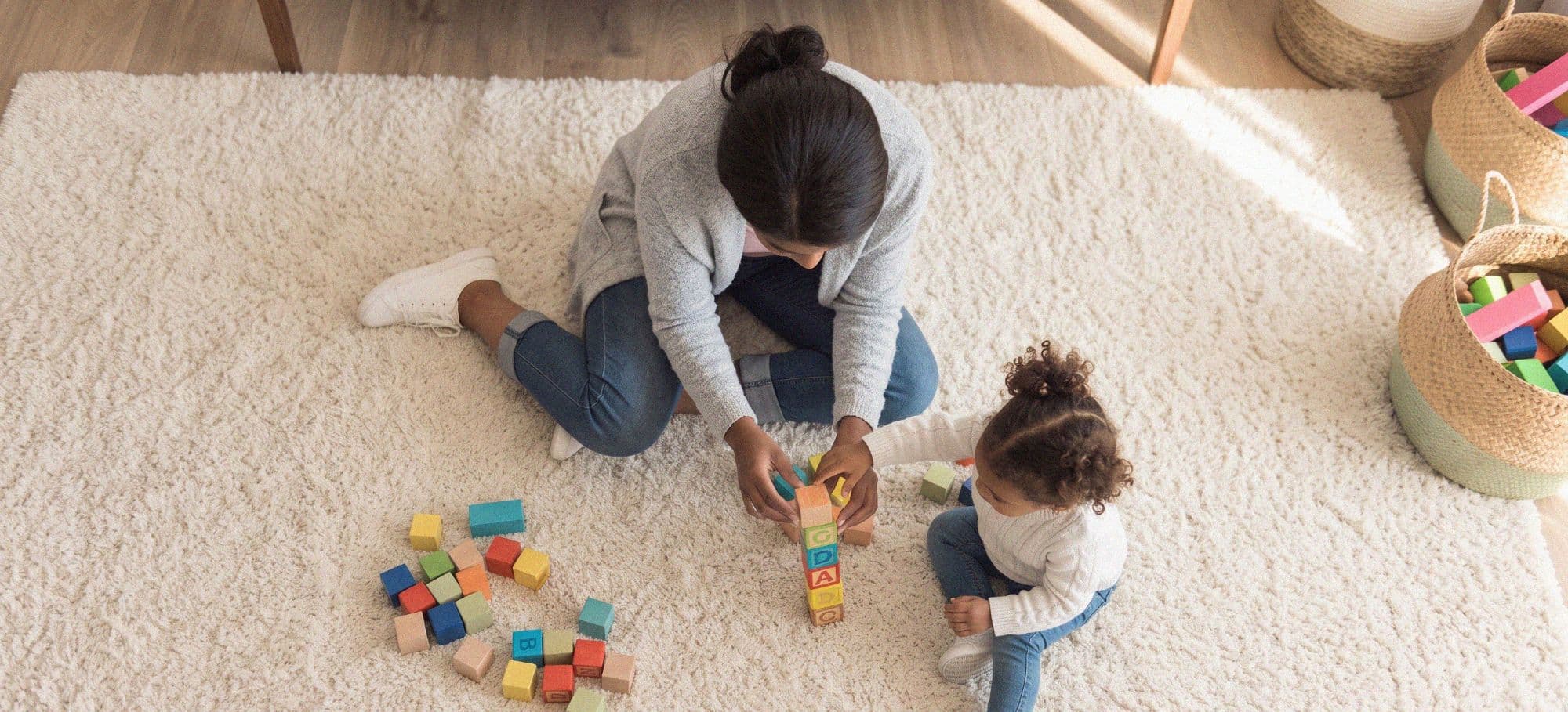 A nanny and a small child building a tower of blocks